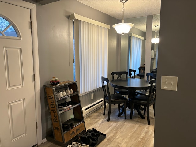 dining space with a textured ceiling, a baseboard radiator, and light hardwood / wood-style floors