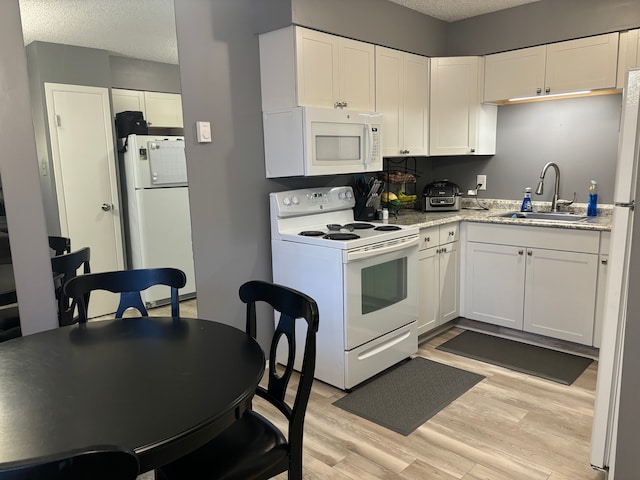 kitchen with sink, light hardwood / wood-style floors, a textured ceiling, white appliances, and white cabinets