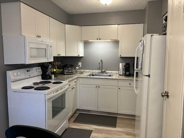 kitchen featuring a textured ceiling, sink, light hardwood / wood-style floors, and white appliances