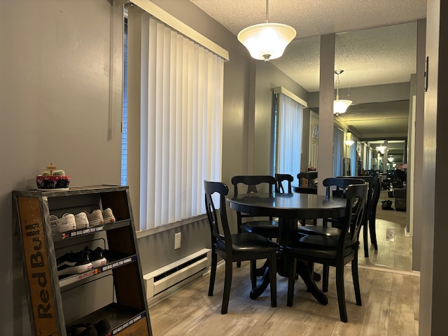 dining area featuring hardwood / wood-style flooring, a textured ceiling, and a baseboard heating unit