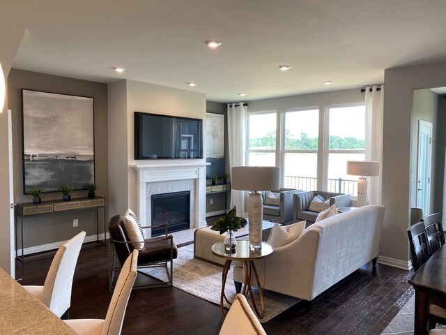 living room featuring a tiled fireplace and dark hardwood / wood-style flooring