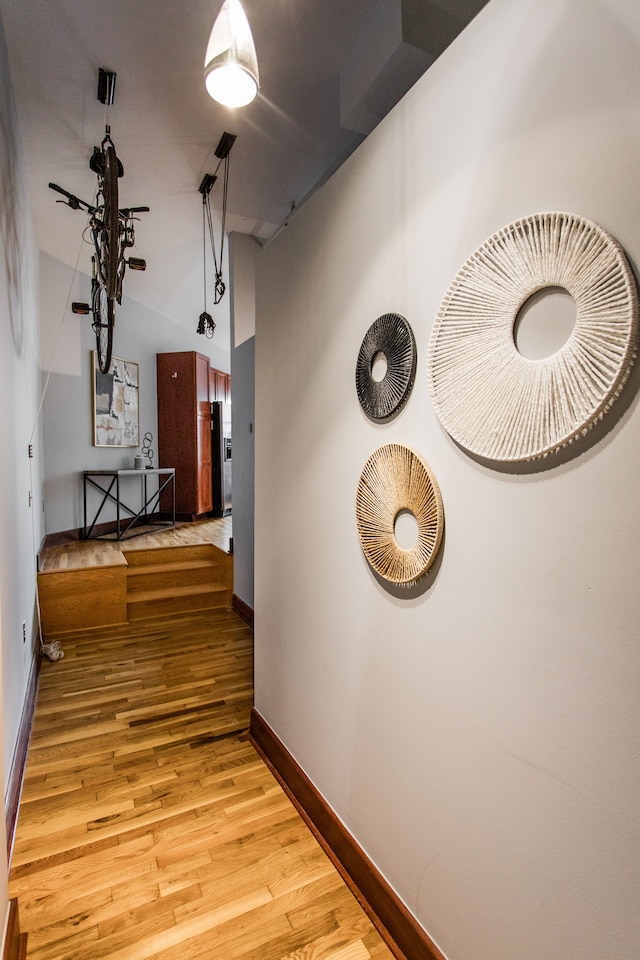 hall featuring a towering ceiling and light hardwood / wood-style flooring