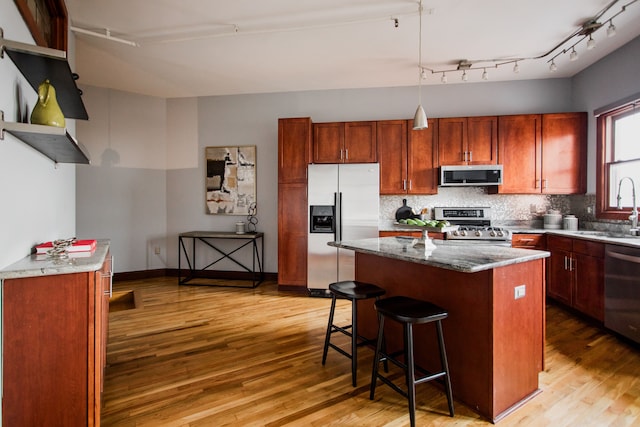 kitchen with sink, backsplash, stainless steel appliances, and a center island