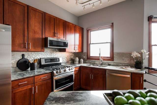 kitchen featuring appliances with stainless steel finishes, sink, backsplash, and light stone counters