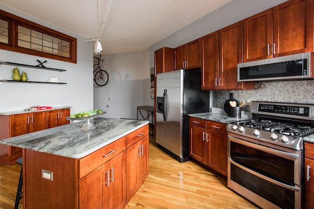 kitchen with appliances with stainless steel finishes, a center island, light stone counters, tasteful backsplash, and light hardwood / wood-style floors