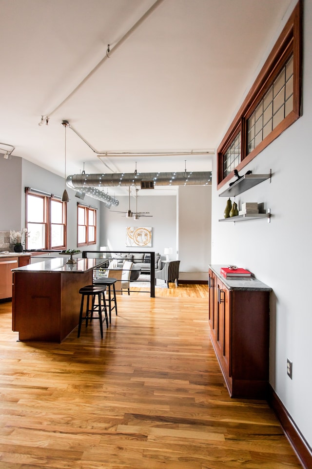 kitchen with pendant lighting, a breakfast bar, hardwood / wood-style floors, and dishwasher