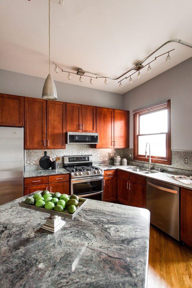 kitchen featuring extractor fan, sink, appliances with stainless steel finishes, pendant lighting, and dark stone counters