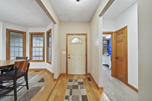 foyer featuring light wood-type flooring and a textured ceiling