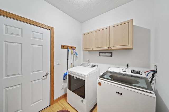 washroom featuring cabinets, a textured ceiling, separate washer and dryer, and light hardwood / wood-style flooring