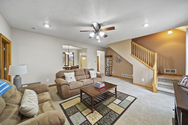 carpeted living room featuring ceiling fan with notable chandelier and a textured ceiling