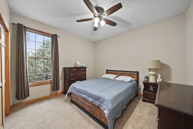 bedroom with ceiling fan, light colored carpet, and a textured ceiling