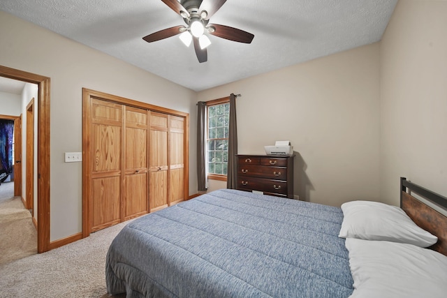 bedroom featuring a textured ceiling, a closet, ceiling fan, and light colored carpet