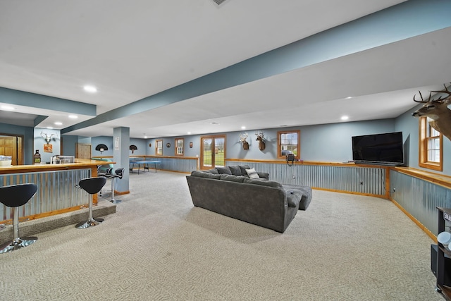 living room with carpet flooring, wood walls, and bar