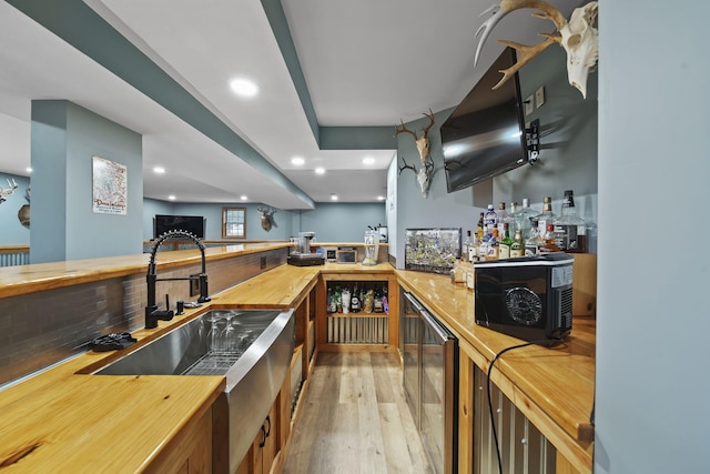 bar with backsplash, light hardwood / wood-style flooring, beverage cooler, and sink