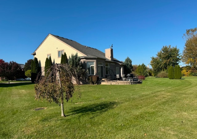 view of side of property with a patio and a lawn