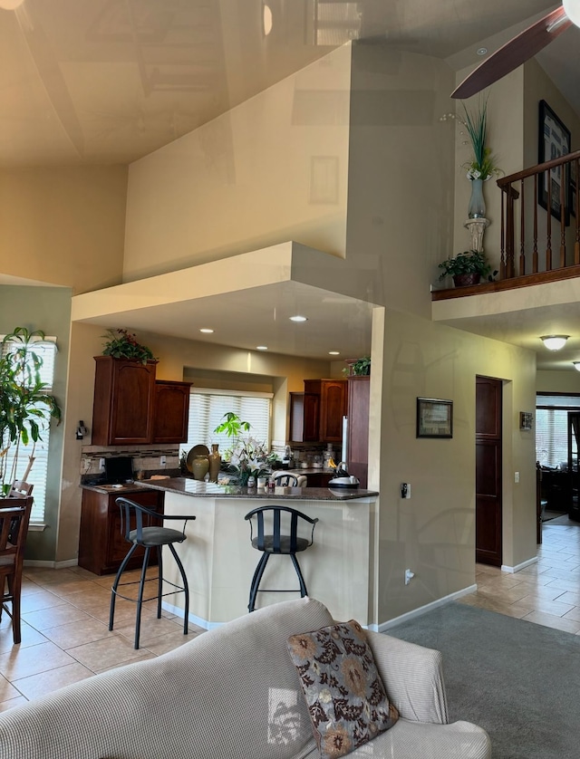 kitchen with a high ceiling, a breakfast bar, a wealth of natural light, and kitchen peninsula