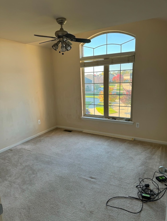 carpeted empty room featuring plenty of natural light and ceiling fan