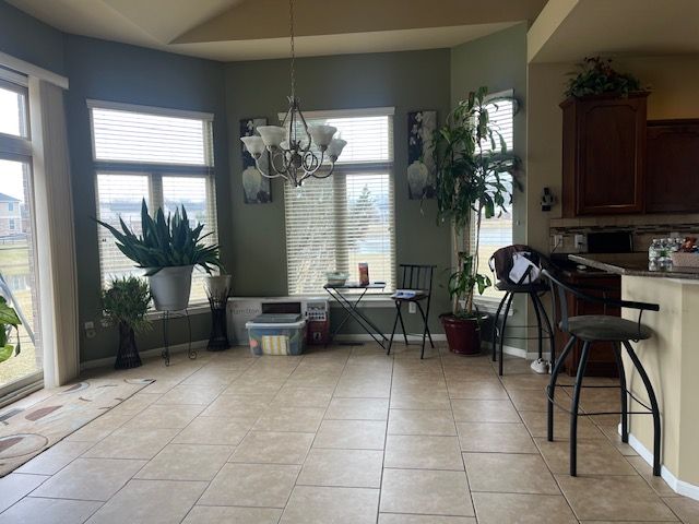 22031 Goldenwillow Dr, Macomb, MI 48044 - dining room featuring light tile patterned floors, a notable chandelier, and a healthy amount of sunlight