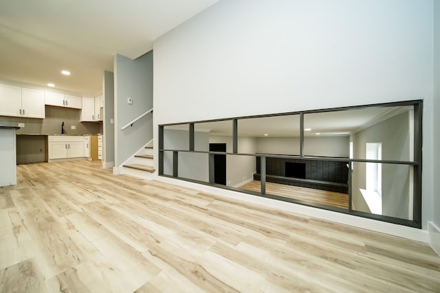 unfurnished living room featuring light hardwood / wood-style flooring, ornamental molding, and sink