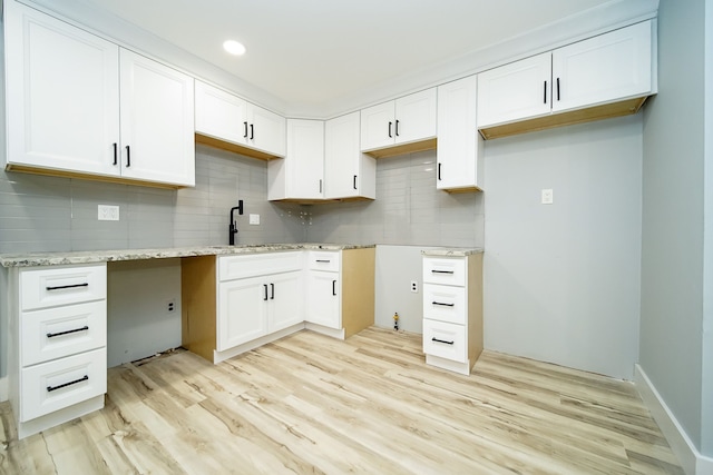 kitchen featuring backsplash, light stone counters, sink, light hardwood / wood-style flooring, and white cabinets