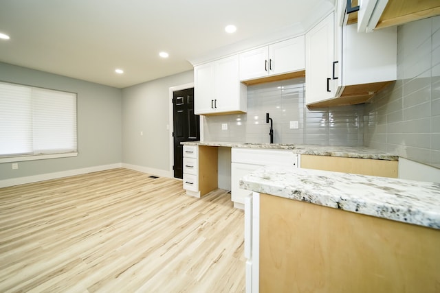 kitchen featuring white cabinetry, sink, light stone countertops, tasteful backsplash, and light hardwood / wood-style flooring