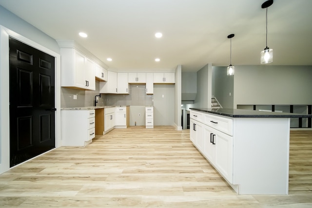 kitchen with decorative backsplash, white cabinetry, a kitchen island, and light wood-type flooring