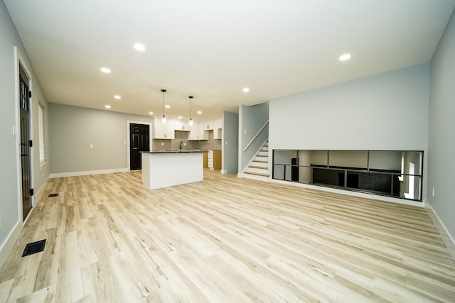 unfurnished living room featuring sink and light hardwood / wood-style flooring