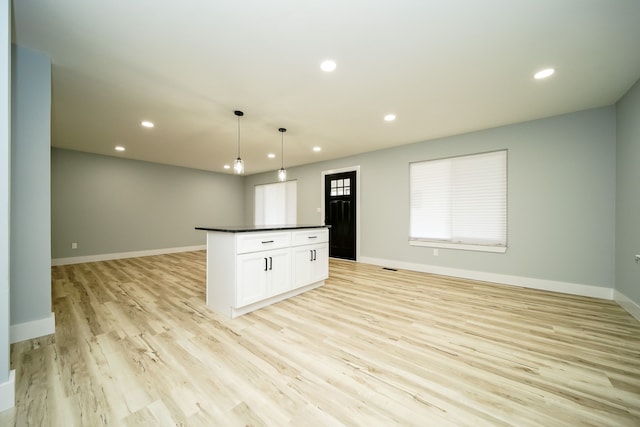 kitchen with a center island, white cabinets, pendant lighting, and light hardwood / wood-style floors