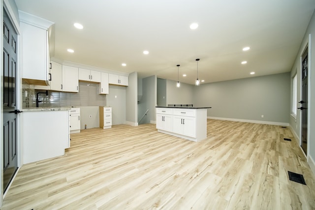 kitchen featuring white cabinets, pendant lighting, light wood-type flooring, and backsplash