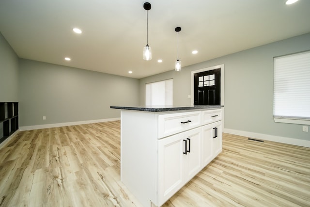 kitchen with white cabinets, decorative light fixtures, a kitchen island, and light wood-type flooring