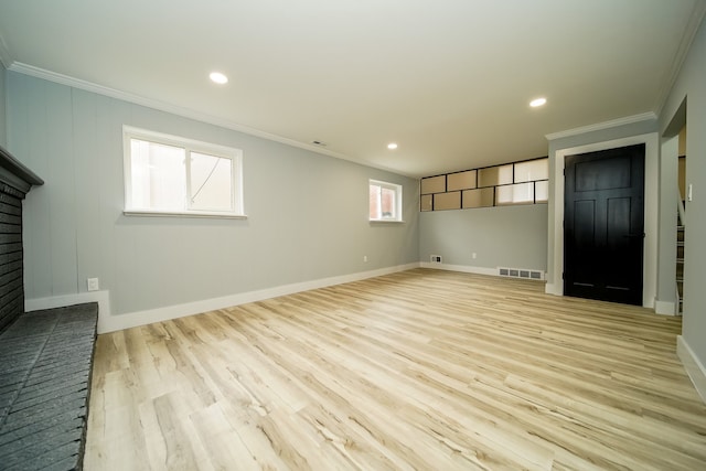 interior space featuring crown molding, light hardwood / wood-style flooring, and a brick fireplace