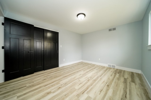 unfurnished bedroom with light wood-type flooring and a closet