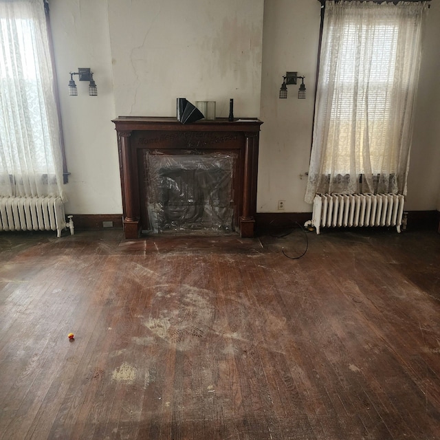 unfurnished living room with radiator, wood-type flooring, and a fireplace