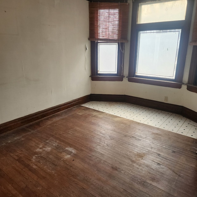 unfurnished room featuring wood-type flooring and baseboards