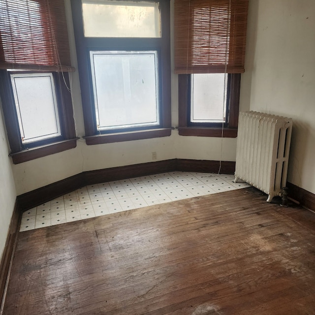 empty room with radiator, light wood-type flooring, and baseboards