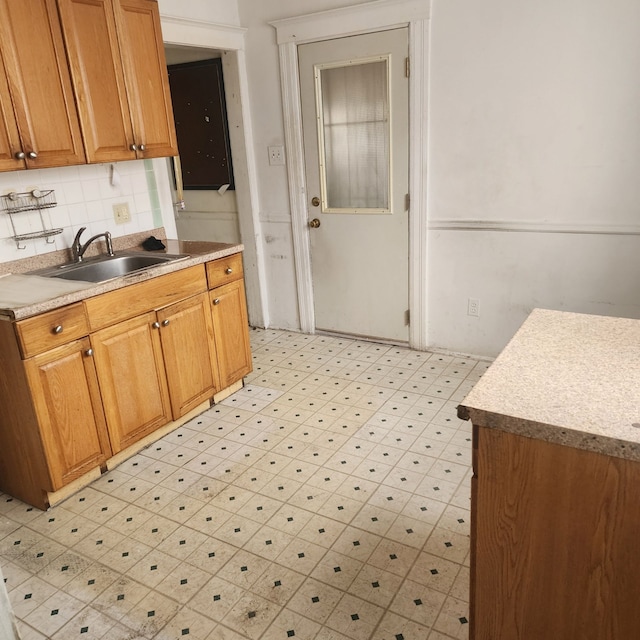 kitchen with light countertops, a sink, backsplash, and light floors