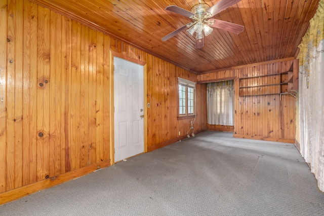 carpeted empty room featuring wooden walls, crown molding, ceiling fan, and wood ceiling