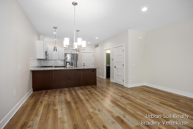 kitchen featuring stainless steel appliances, light stone counters, white cabinets, decorative backsplash, and kitchen peninsula