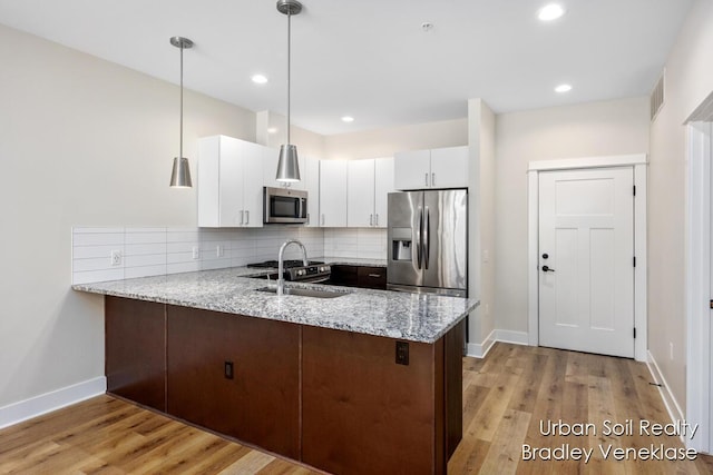 kitchen with white cabinetry, stainless steel appliances, decorative light fixtures, light stone countertops, and dark brown cabinets