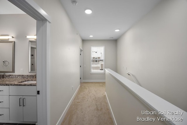 hallway with sink and light colored carpet