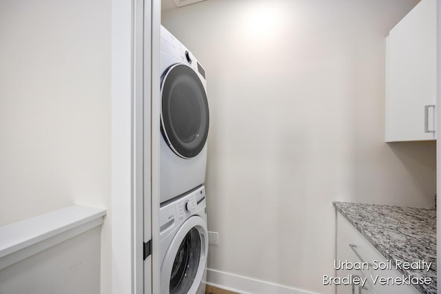 laundry room featuring stacked washing maching and dryer and cabinets