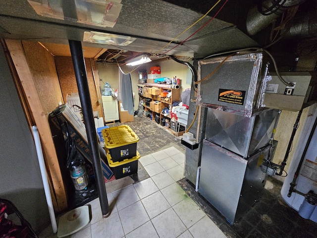 basement featuring tile patterned flooring, washer / clothes dryer, and heating unit