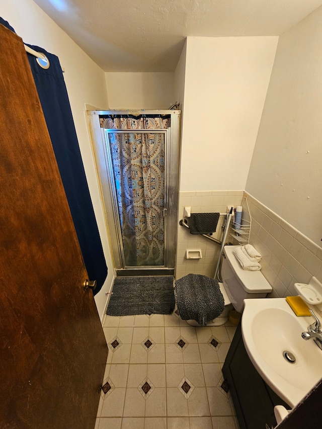 bathroom with curtained shower, tile patterned floors, toilet, vanity, and tile walls