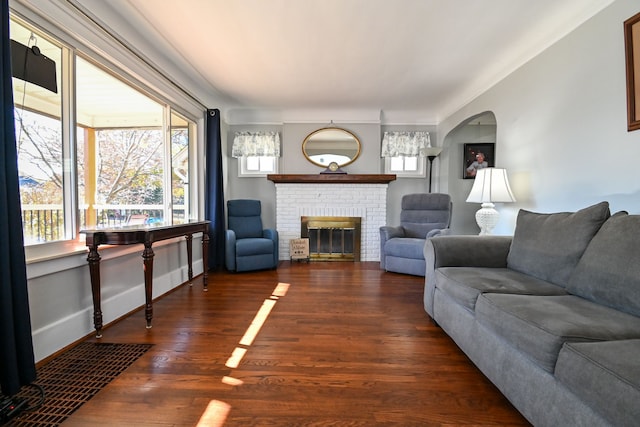 living room with dark hardwood / wood-style flooring and a brick fireplace