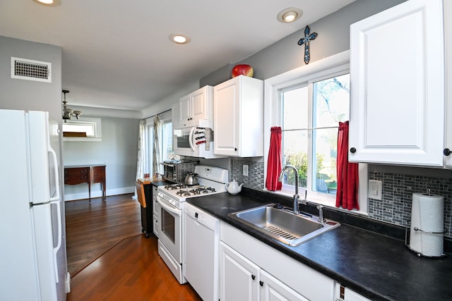 kitchen with tasteful backsplash, white appliances, dark wood-type flooring, sink, and white cabinets