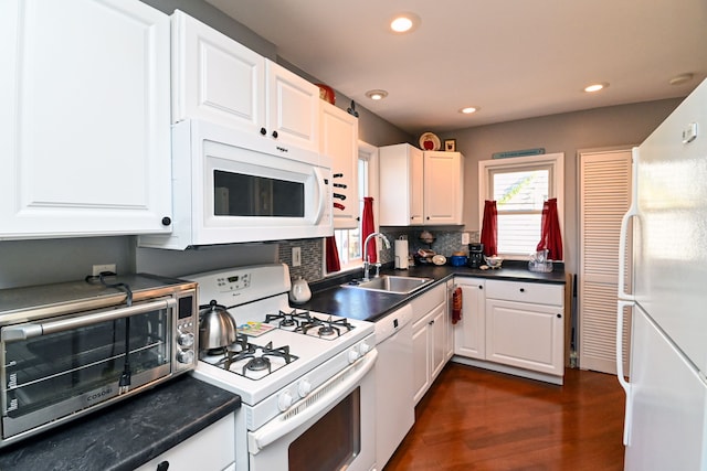 kitchen with white cabinetry, sink, dark wood-type flooring, backsplash, and white appliances