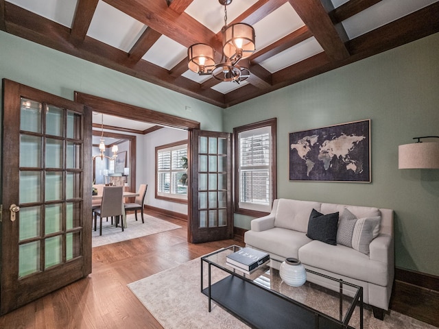 living room featuring coffered ceiling, french doors, an inviting chandelier, beam ceiling, and wood-type flooring