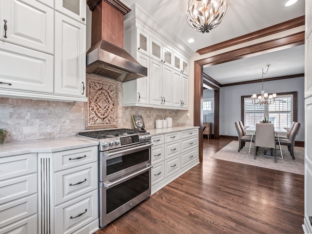 kitchen featuring white cabinetry, double oven range, wall chimney exhaust hood, and a notable chandelier