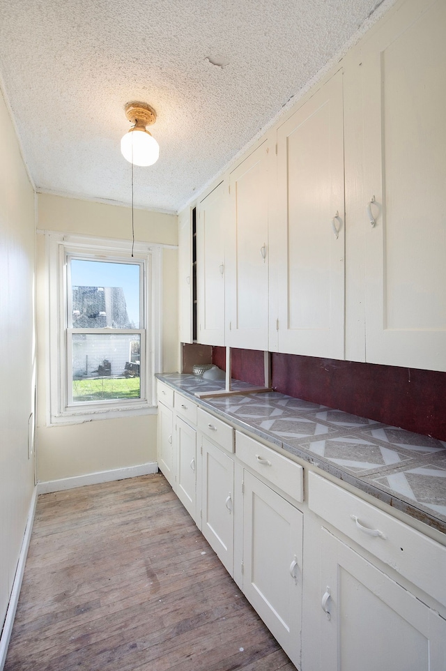 kitchen featuring white cabinets, light hardwood / wood-style floors, light stone countertops, and a textured ceiling