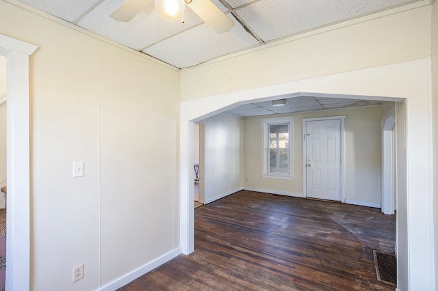 foyer entrance with a drop ceiling, dark wood-type flooring, and ceiling fan